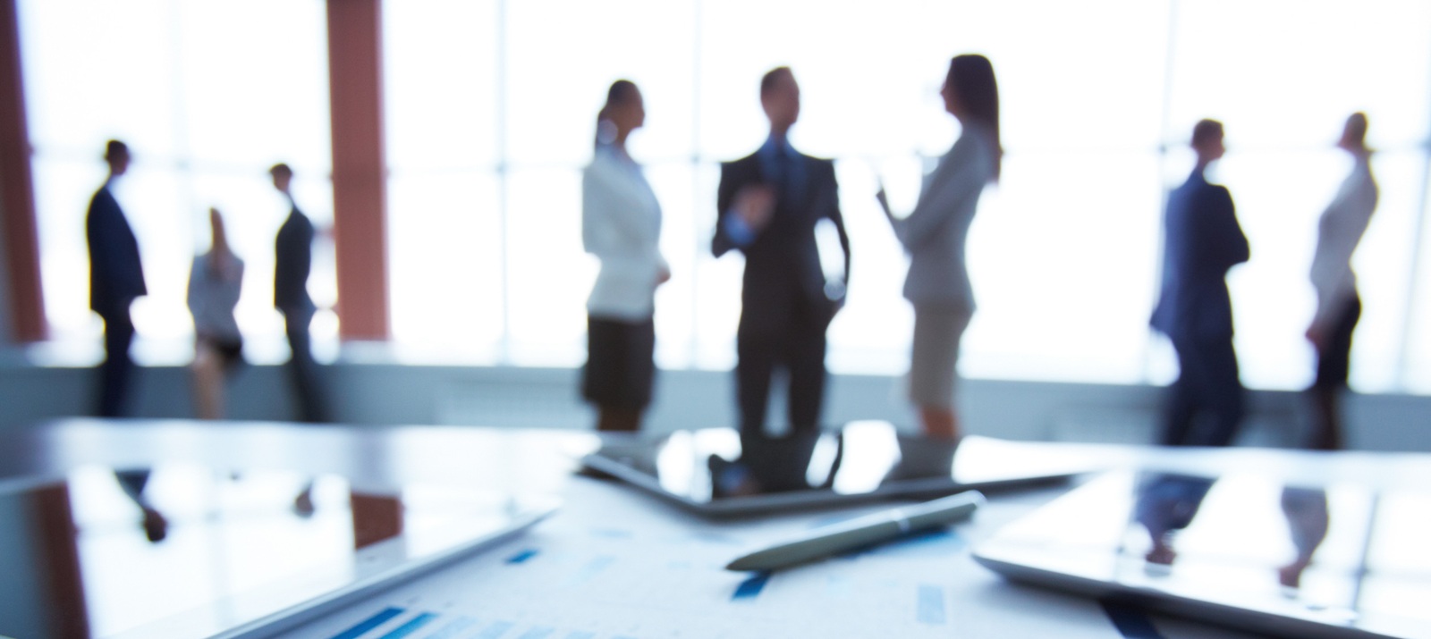 Close-up of business document in clipboard at workplace on background of office workers interacting