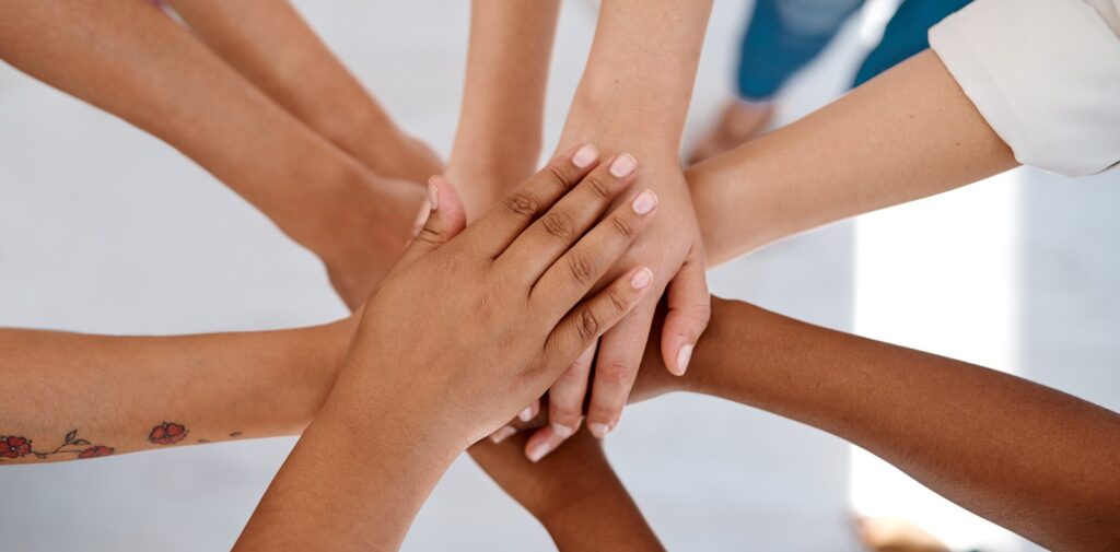 Cropped shot of a group of unrecognizable businesspeople joining hands together in a huddle inside an office.