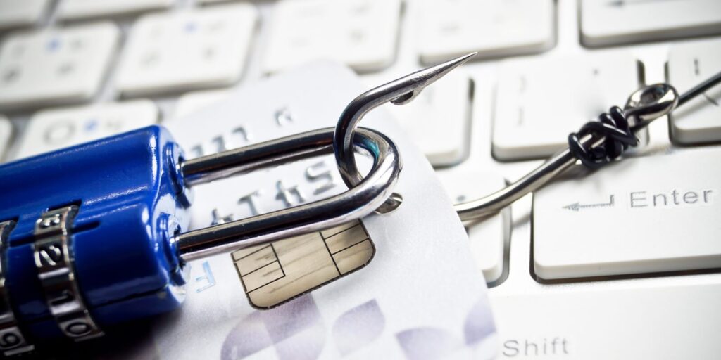 phishing - fish hook with a credit card and security lock on white computer keyboard