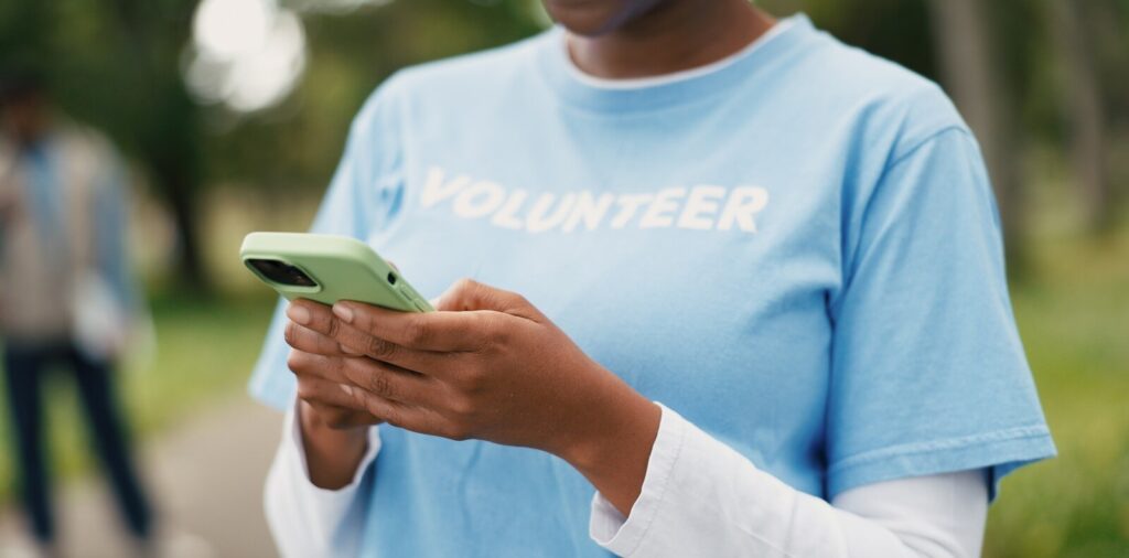 phone and volunteer with woman outdoor for charity, community outreach or food drive
