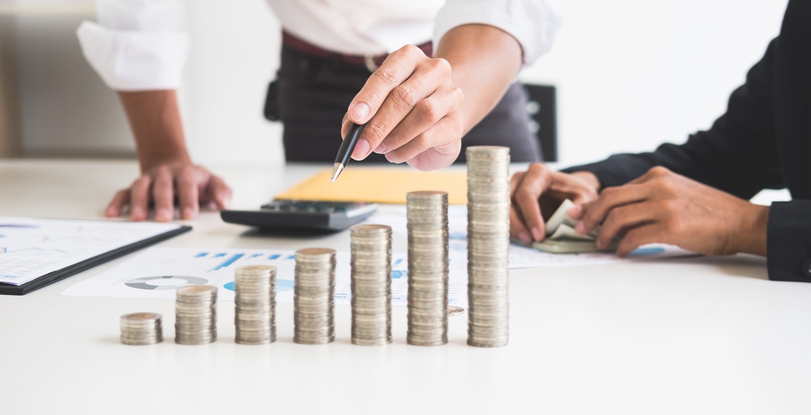 stacks of coins business accounting with saving money concept calculator counting, making notes at home, hand is writes in a notebook