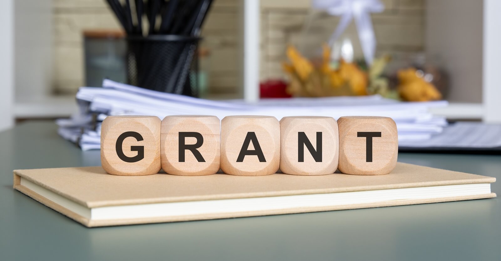 wooden cubes spelling GRANT on a notebook with documents in background