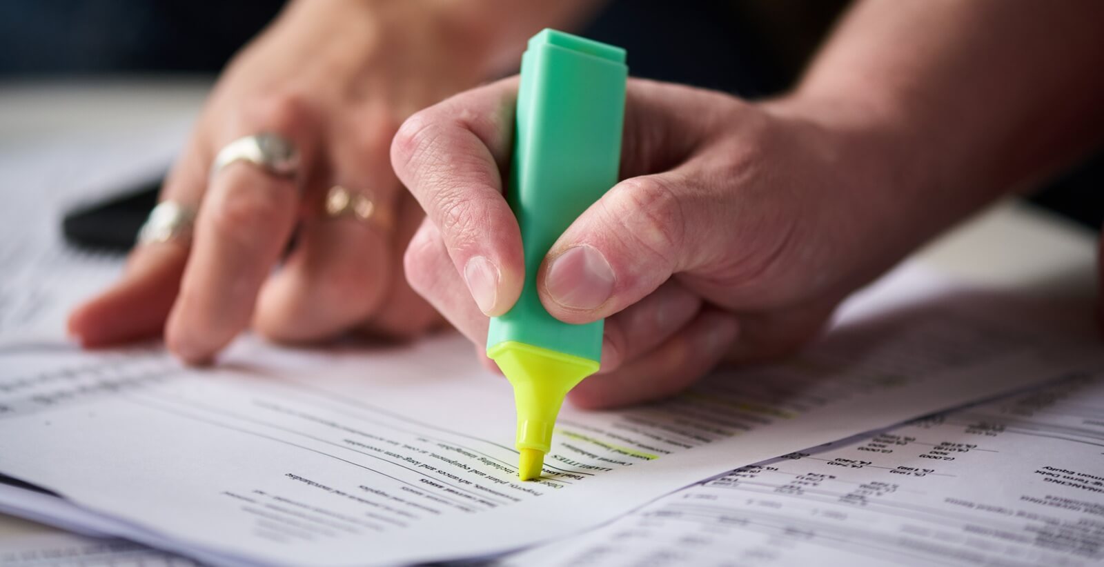 middle aged man highlighting financial documents with green marker while Caucasian middle aged woman assisting