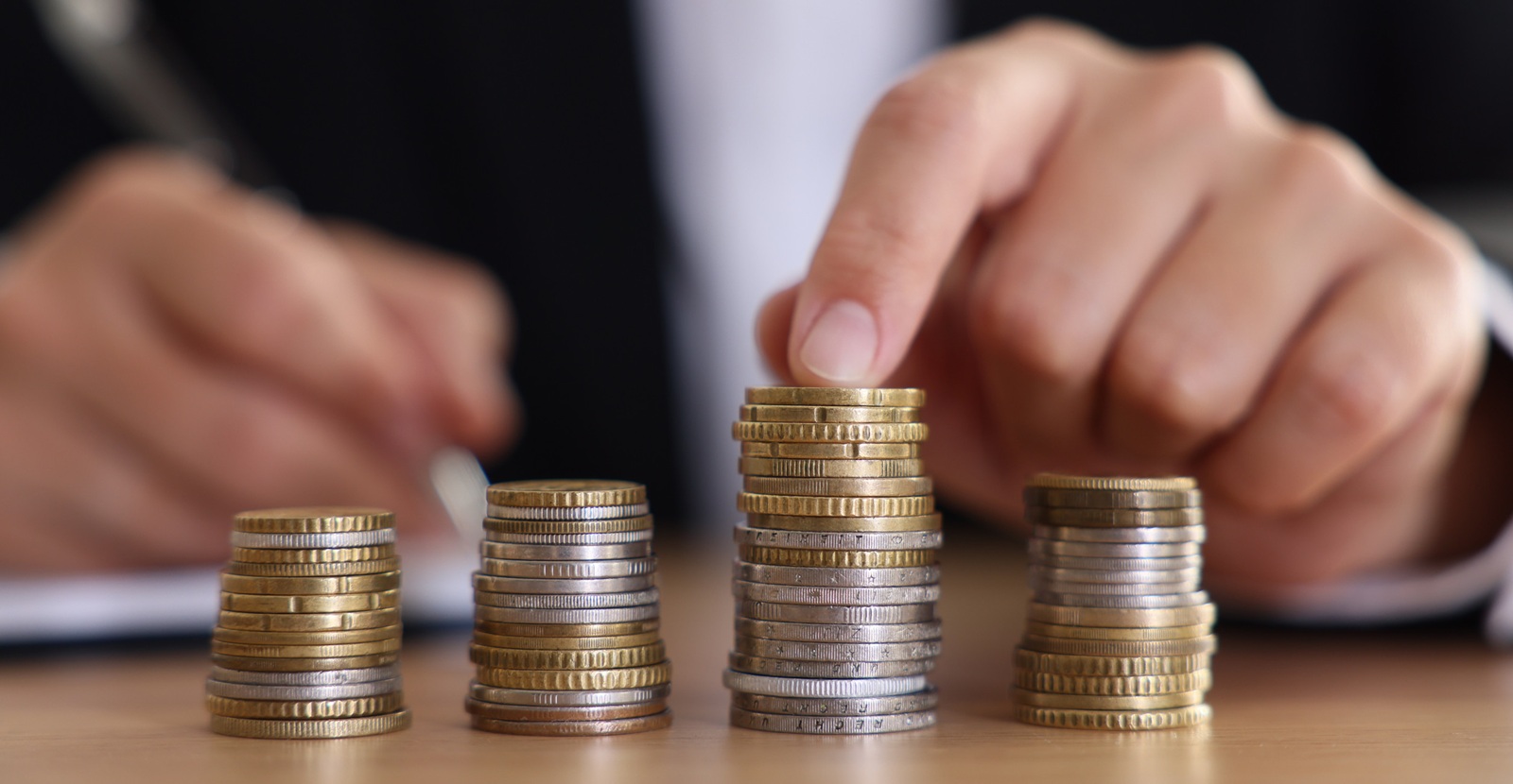 woman counting coins at wooden table indoors