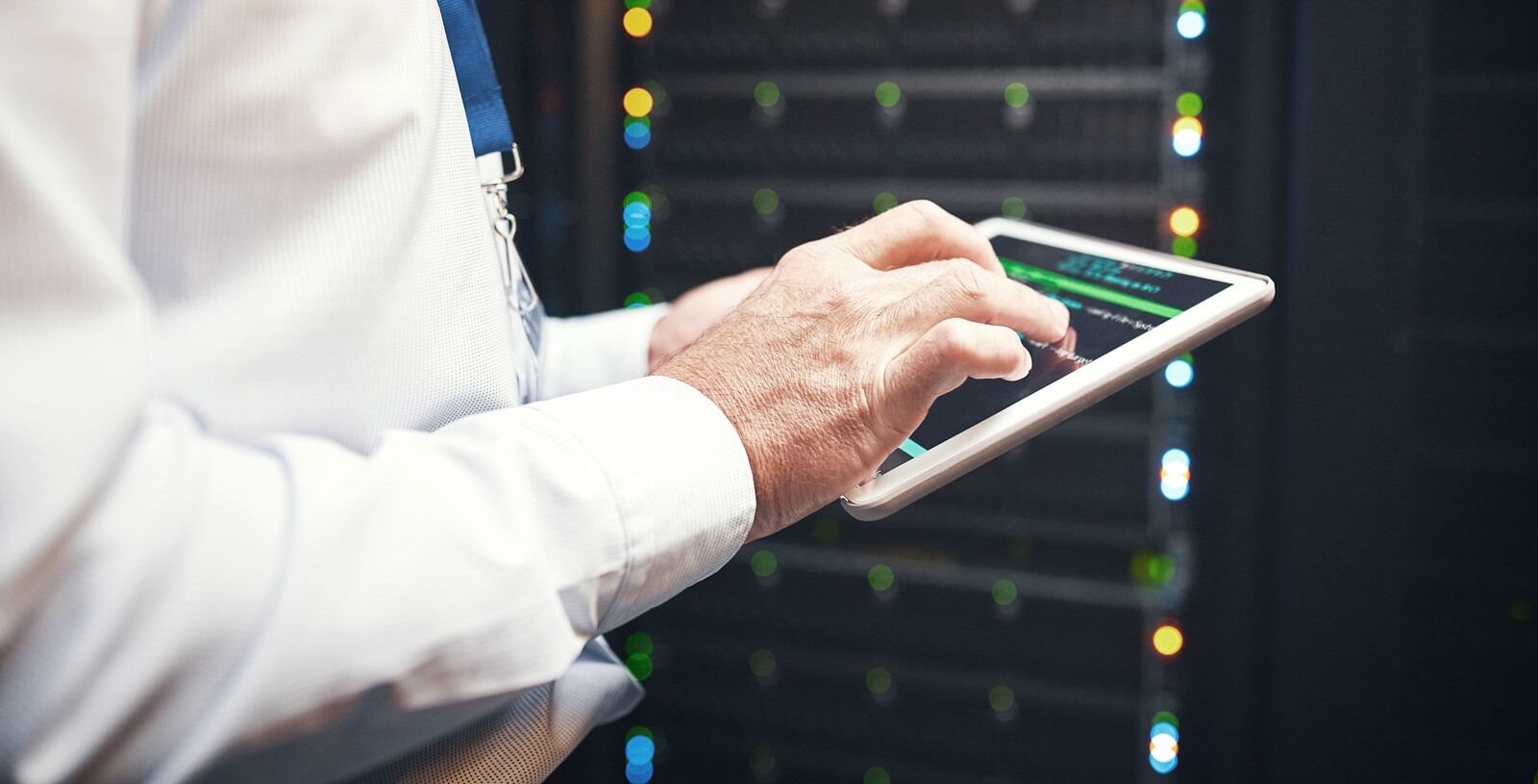 an unrecognisable man using a digital tablet while working in a server room