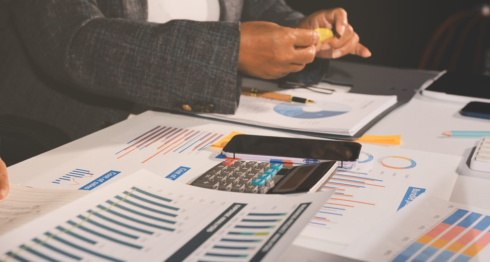 business documents on office table with tablet, smart phone and laptop and two colleagues discussing data