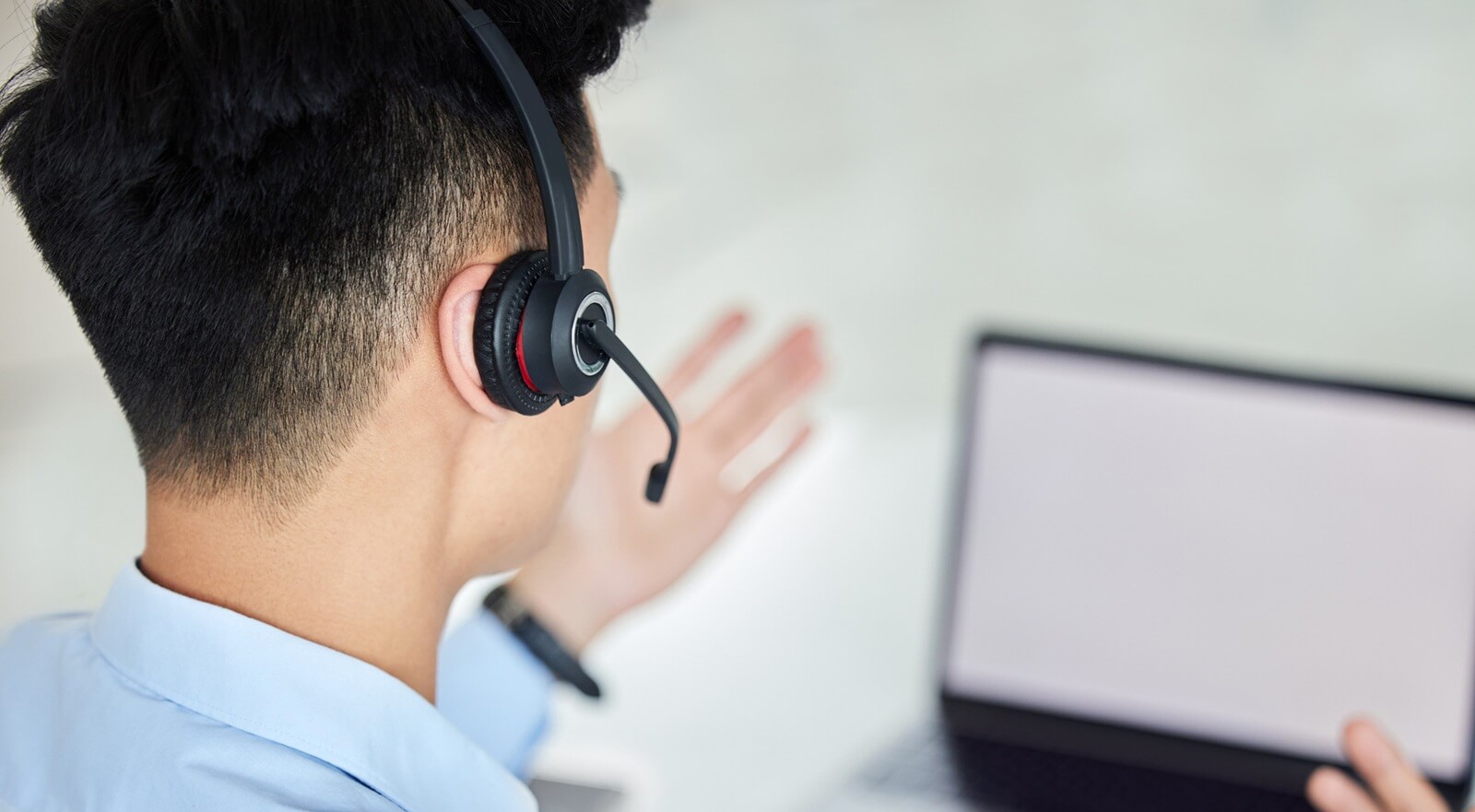 customer service and telemarketing with a man working on a laptop with a headset in his office