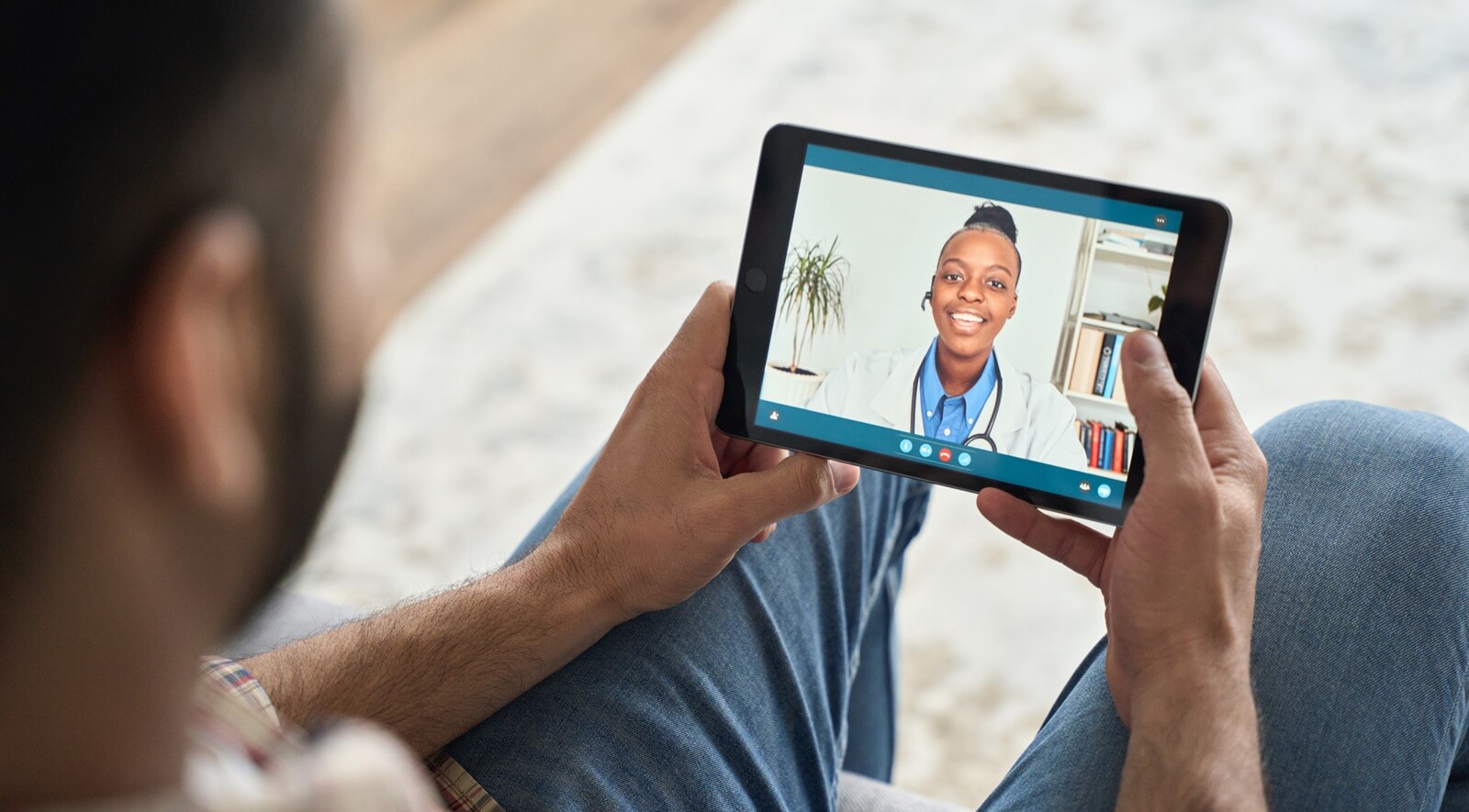 indian man having videocall with female black doctor using tablet