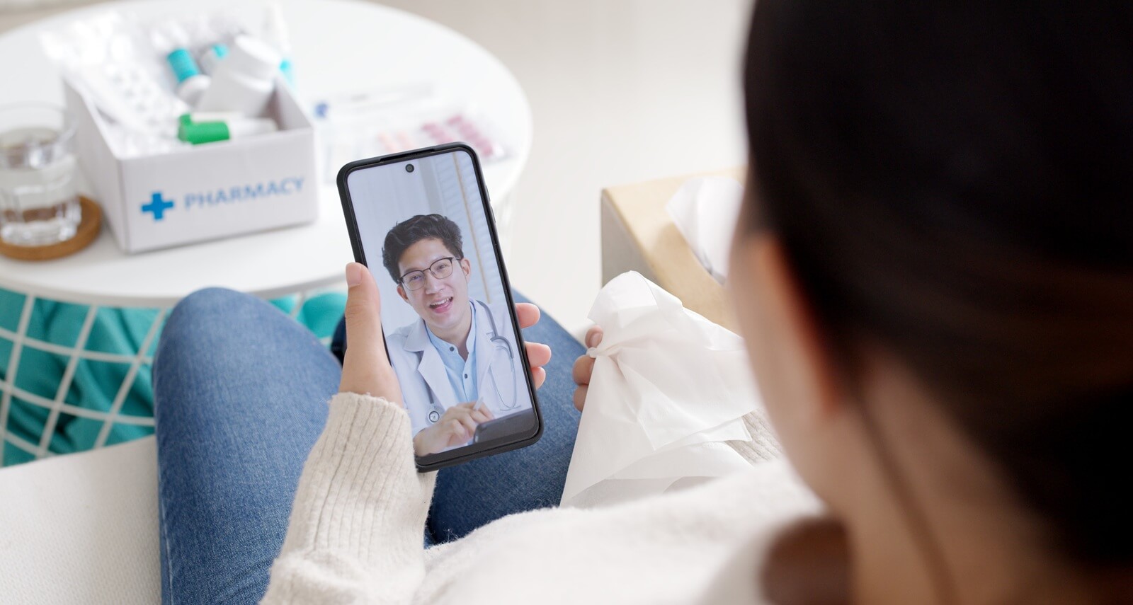 shoulder view of young asia woman talk to doctor on cellphone videocall conference medical app in telehealth telemedicine online service hospital quarantine social distance at home concept