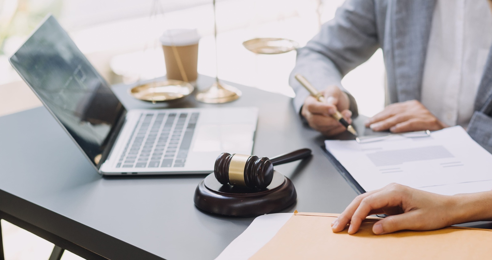business and lawyers discussing contract papers with brass scale on desk in office