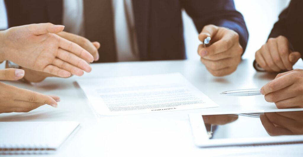 business people and lawyers discussing contract while sitting at the table in office