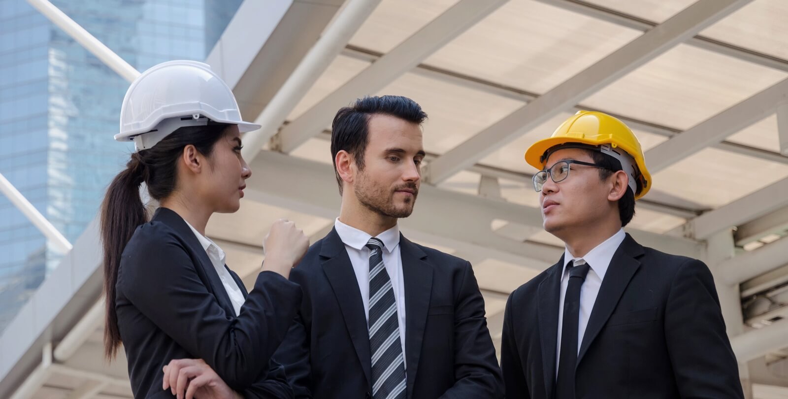 group of business or engineer woman and man with safety helmet about new project building plan and checking their work in modern city