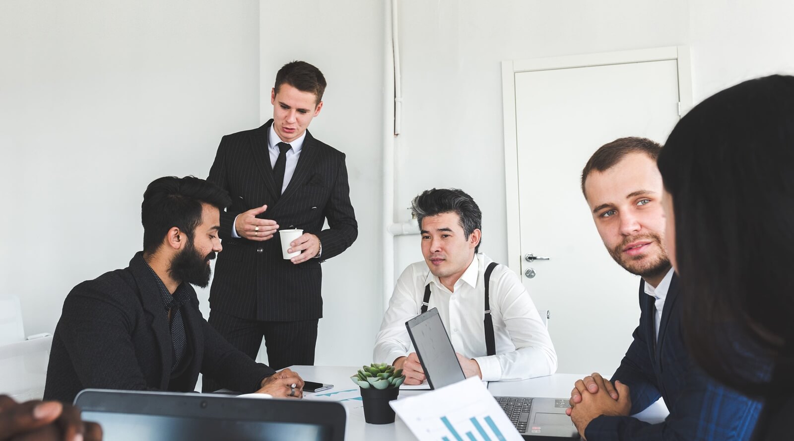 young business people working and communicating while sitting at the office desk together with colleagues sitting