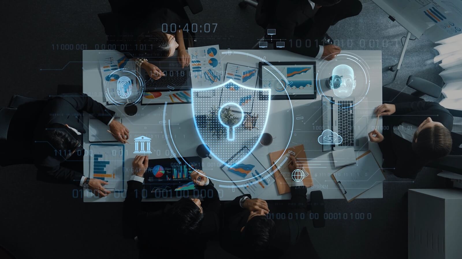 Aerial view of a business meeting focused on cyber security strategies with laptops, charts, and a digital shield symbolizing data protection and safety measures