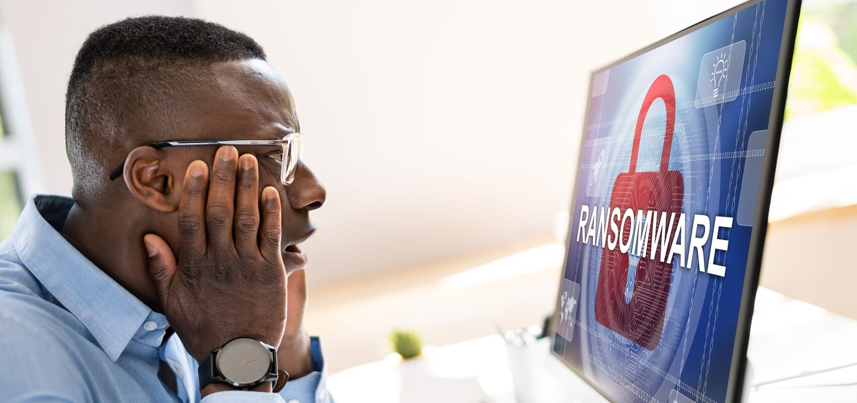 worried businessman looking at computer with ransomware word on the screen
