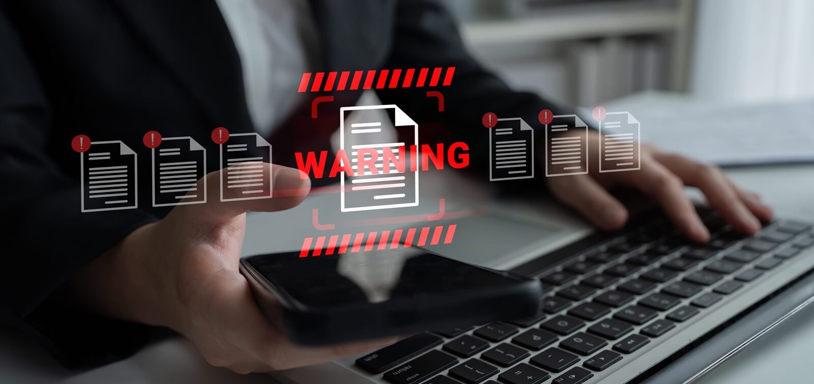 business professional interacts with laptop and smartphone while receiving a warning notification about document status